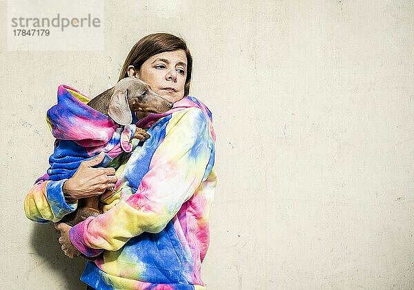 Lateinamerikanische Frau mit ihrem Hund  beide gleich gekleidet. Sie scheinen besorgt zu sein. Grauer Hintergrund. Leerzeichen kopieren