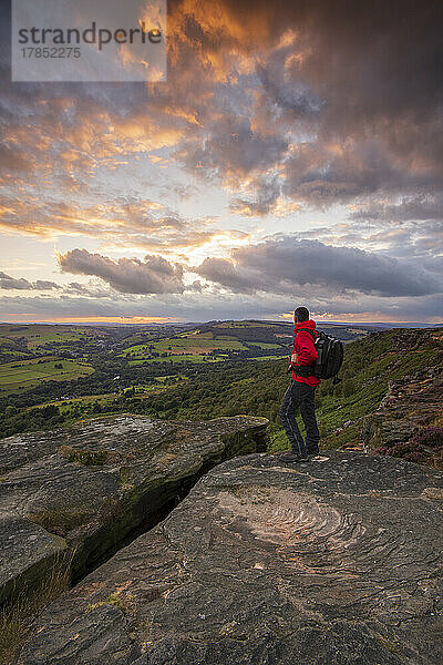 Ein Wanderer steht bei Sonnenuntergang auf Curbar Edge  Derbyshire  Peak District  Derbyshire  England  Vereinigtes Königreich  Europa