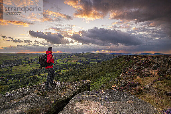 Ein männlicher Wanderer steht bei Sonnenuntergang auf Curbar Edge  Peak District  Derbyshire  England  Vereinigtes Königreich  Europa