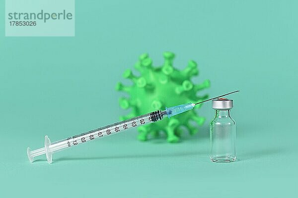 Impfstofffläschchen mit Spritze und Coronavirus Modell im Hintergrund