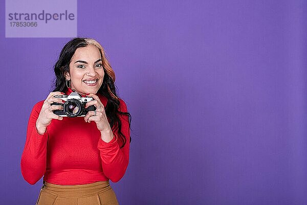 Attraktive junge Frau  die ein Foto mit ihrer Filmkamera vor einem violetten Hintergrund macht. . Leerzeichen kopieren
