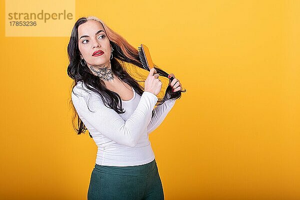 Attraktive Frau kämmt ihr Haar über gelben Hintergrund