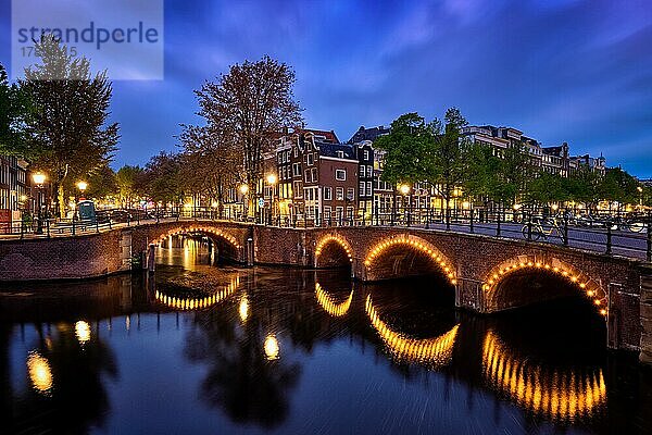 Nachtansicht der Stadt Amterdam mit Gracht  Brücke und mittelalterlichen Häusern in der Abenddämmerung beleuchtet. Amsterdam  Niederlande  Europa