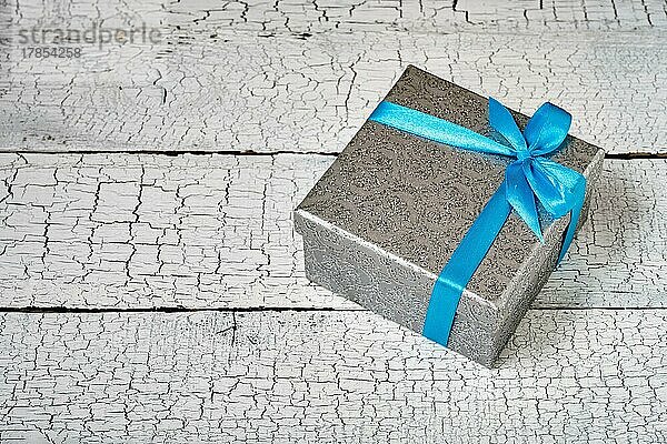 Geschenk Geburtstag Weihnachtsgeschenk Konzept  silberne Geschenk-Box mit blauem Band auf weiß lackiertem Holz Hintergrund. Ansicht von oben