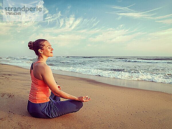 Vintage Retro-Hipster-Effekt Bild der Frau tun Yoga meditieren und entspannen in Padmasana Lotus Pose mit Kinn Mudra im Freien am tropischen Strand bei Sonnenuntergang