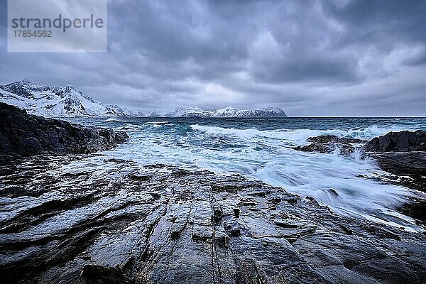 Wellen der norwegischen See  die an einer felsigen Küste im Fjord zerschellen. Vikten  Lofoten Inseln  Norwegen  Europa