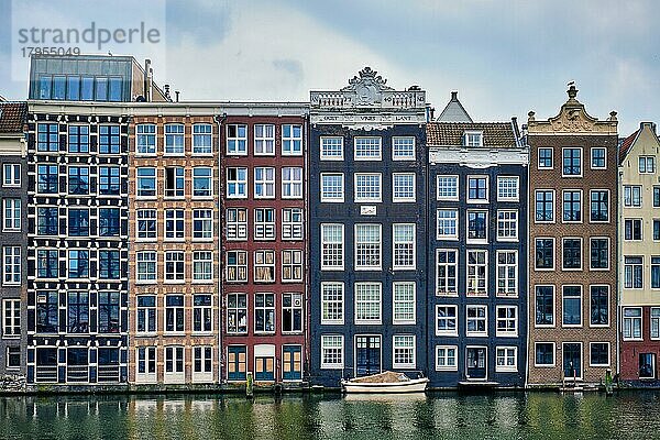 Reihe typischer Häuser und Boot auf dem Amsterdamer Damrak-Kanal mit Spiegelung. Amsterdam  Niederlande  Europa