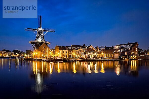 Blick auf das Stadtbild von Harlem mit dem Wahrzeichen  der Windmühle De Adriaan am Fluss Spaarne  in der Nacht beleuchtet. Harlem  Niederlande  Europa