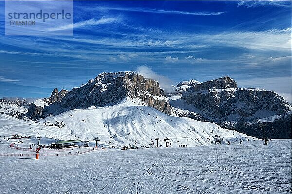 Blick auf eine Piste in einem Skigebiet mit Skifahrern in den Dolomiten in Italien