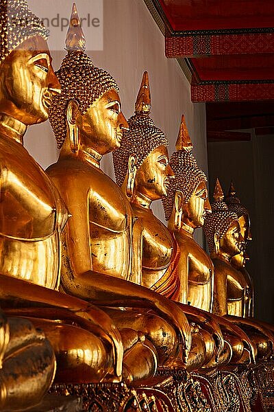 Reihe von vergoldeten sitzenden Buddha-Statuen im buddhistischen Tempel Wat Pho  Bangkok  Thailand. Niedriger Blickwinkel  Fokus auf den 3. von links