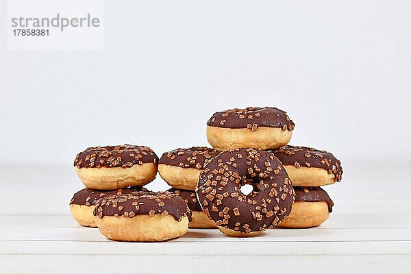 Donuts mit Schokolade glasiert und mit Streuseln auf weißem hölzernen Hintergrund mit Kopie Raum