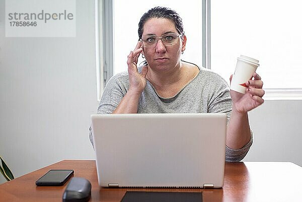 Porträt einer Frau  die an ihrem Laptop arbeitet und Kaffee trinkt