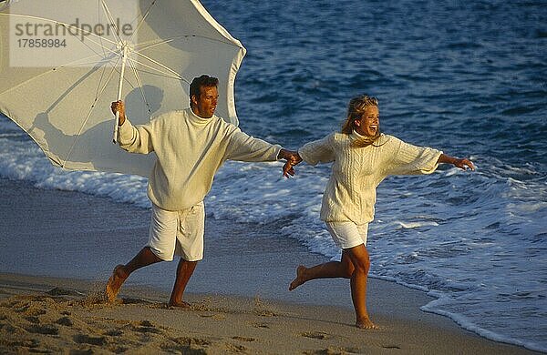 Paar am Strand  rennend  mit Sonnenschirm