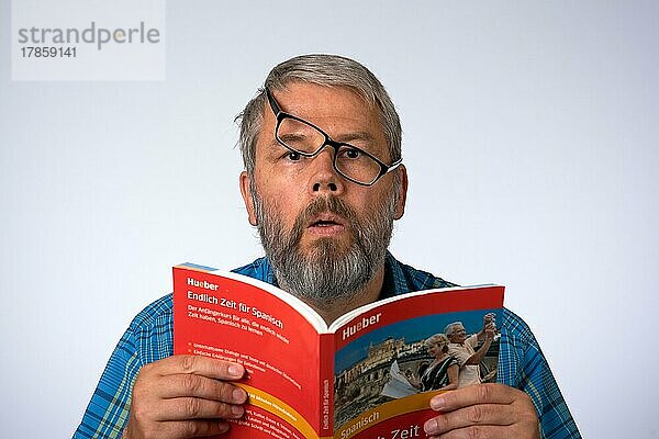 Mann  55 Jahre im Studio  Symboldbild Verwirrung  lernt eine Sprache  liest in einem Buch
