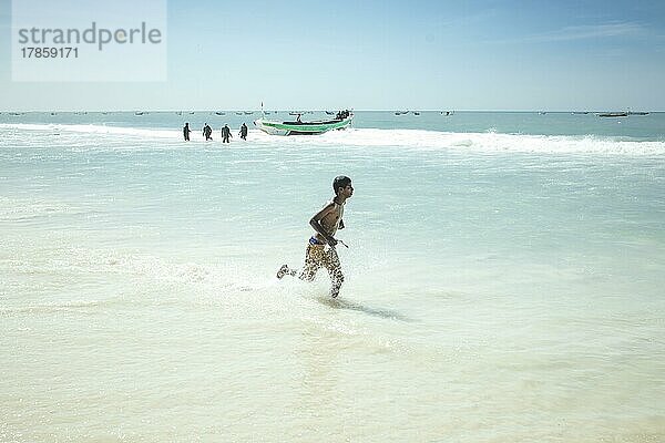 Traditioneller Fischereistrand  Plage des Pêcheurs Traditionnels  Ankunft der Fischerboote  ein Junge sammelt einzelne Fischer  die ins Wasser fallen  Nouakchott  Mauretanien  Afrika