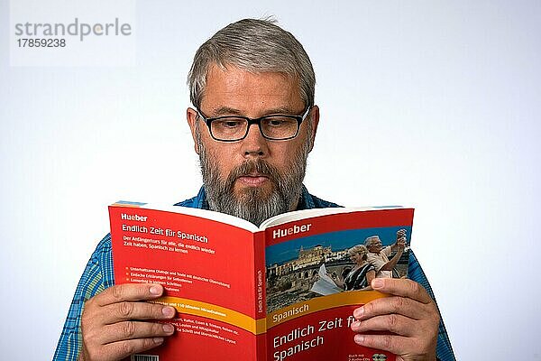 Mann  55 Jahre im Studio  Symboldbild Lernen  lernt eine Sprache  liest in einem Buch