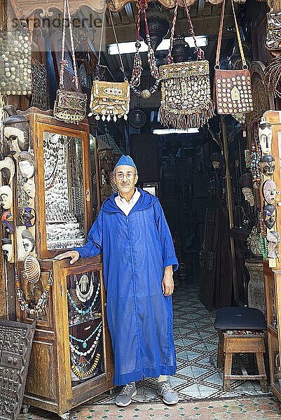 Marokkanischer Mann im traditionellen Djelabba oder Kapuzenmantel am Eingang zu seinem Shop  Fes  Marokko  Afrika