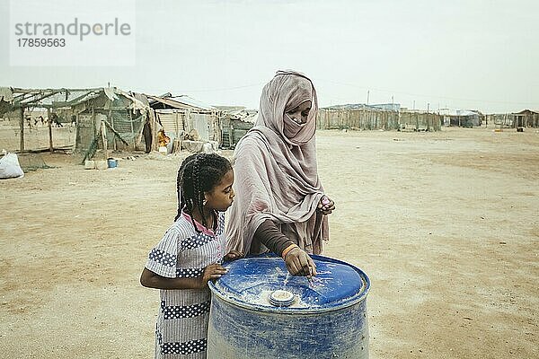 Eine Frau beschriftet die Wassertonne ihres Hauses mit Nagellack  Fischerdorf am Atlantik  Nouamghar  Mauretanien  Afrika