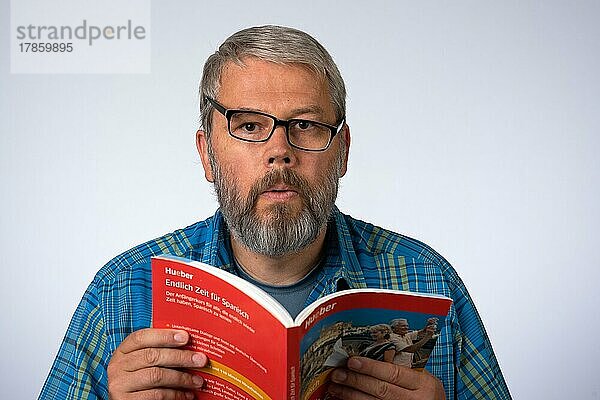 Mann  55 Jahre im Studio  Symboldbild Verwirrung  lernt eine Sprache  liest in einem Buch