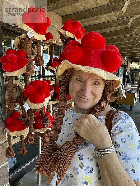 Ältere Frau kokettiert mit Fake Bollenhut  Tracht  Perücke  Zöpfe  Souvenir  Souvenirladen  Mummelsee  Seebach  Nationalpark Schwarzwald  Baden-Württemberg  Deutschland  Europa