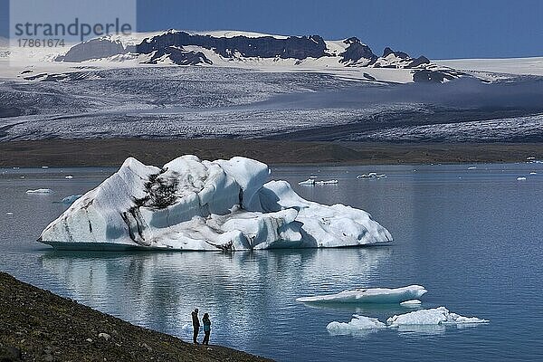 Zwei Menschen vor einem Eisberg an der Gletscherlagune Jökulsarlon  Vatnajökull-Nationalpark  Hornarfjördur  Island  Europa