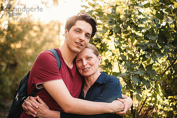 Porträt einer glücklichen Mutter und ihres Sohnes  die sich im Sommer im Freien umarmen