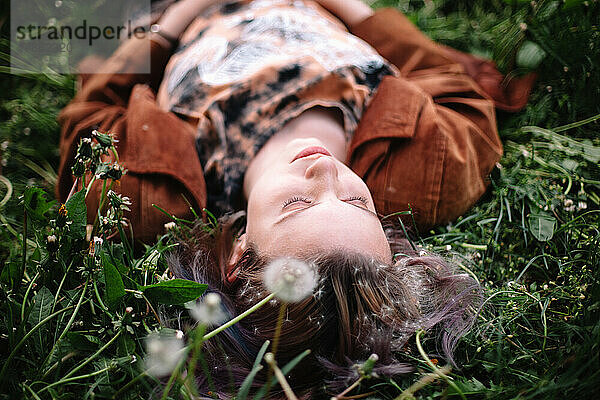 Friedliche junge Frau  die im Frühling auf Gras liegt
