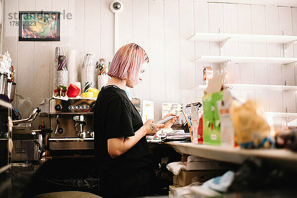 Weibliche Barista arbeitet an der Kasse an einem Tablet im Café