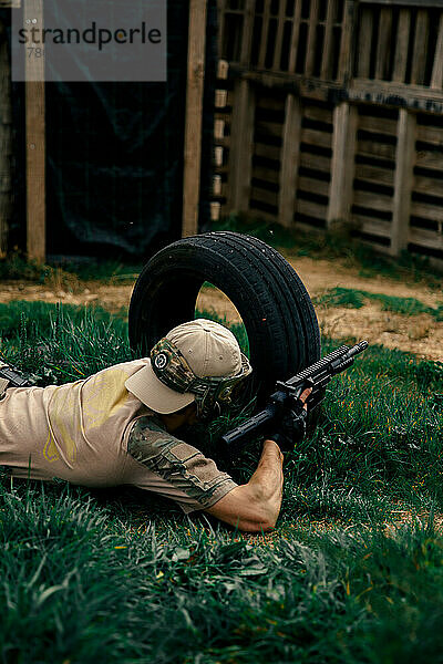 Soldat liegt im Gras und zielt in einem Airsoft-Match mit einer Waffe