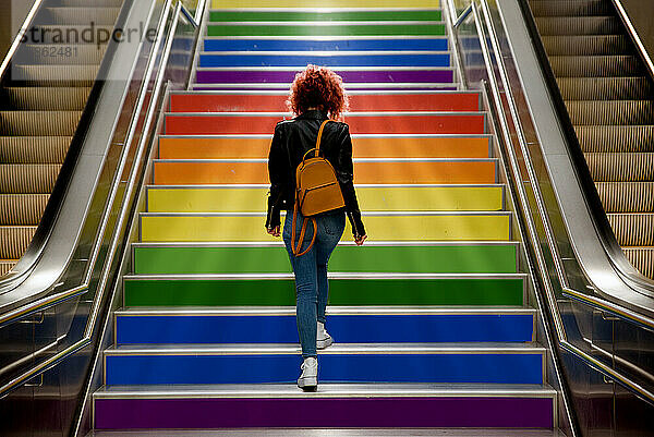 Mädchen  das am Gay-Pride-Tag mit der LGBT-Flagge die Treppe hinaufgeht