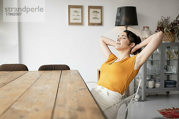 Entspannende Frau sitzt zu Hause am Esstisch und entspannt sich