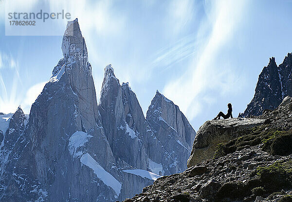 Die Silhouette eines Wanderers zeichnet sich vor den gewaltigen Gipfeln des Cerro Torre ab