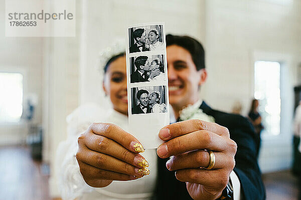 Bride and groom smile holding polaroid photograph of them