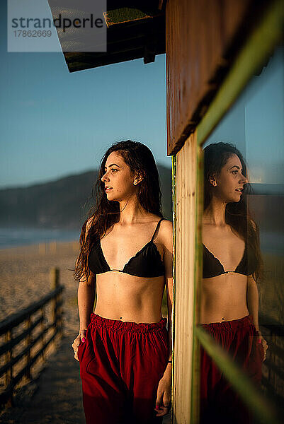 Junge Frau mit Bikini blickt auf den Horizont am Strand