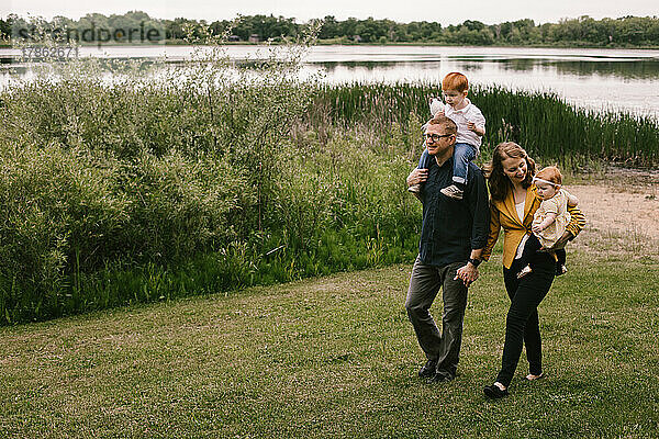 Familie aus Vater  Mutter  Sohn und Tochter spaziert am Seeufer entlang