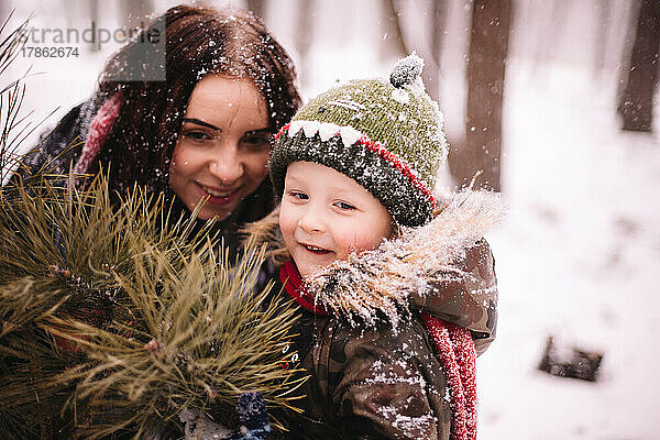 Glückliche Mutter und Sohn stehen im Winter draußen am Weihnachtsbaum