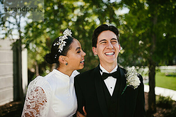 Latina-Braut und gemischtrassiger Bräutigam lachen und lächeln nach der Hochzeit