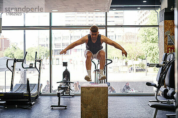 Fitness-Mann trainiert mit einer Holzkiste im Fitnessstudio. Beinabschnitt