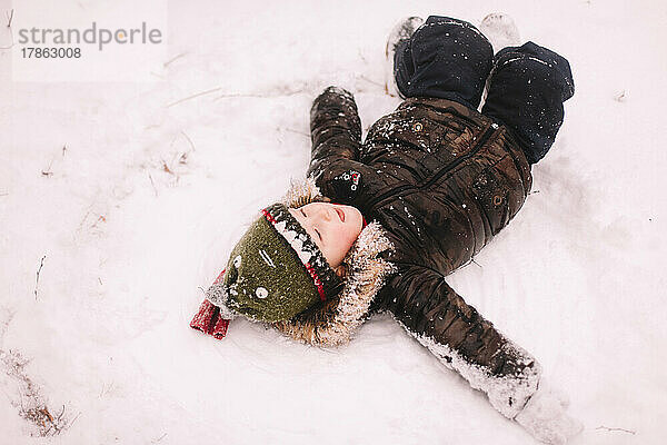 Baby Junge liegt im Winter im Schnee