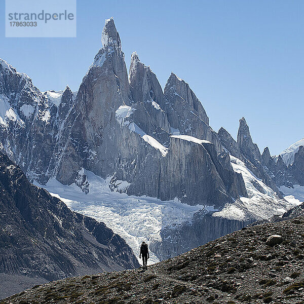 Die Silhouette eines Wanderers zeichnet sich vor den gewaltigen Gipfeln des Cerro Torre ab