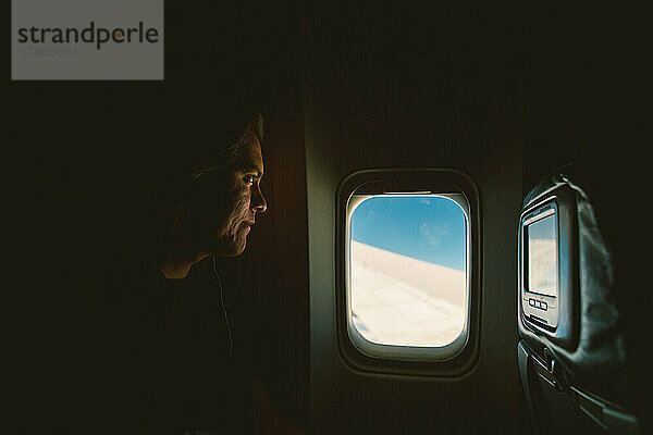 Ein amerikanischer Ureinwohner blickt aus dem Flugzeugfenster auf den blauen Ozean