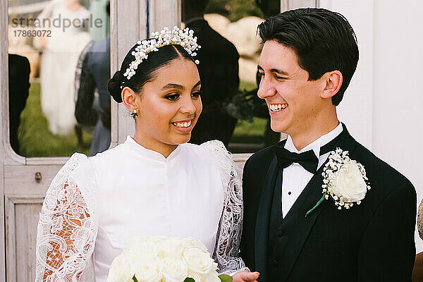 Latina-Braut und gemischtrassiger Bräutigam lächeln nach der Heirat zusammen