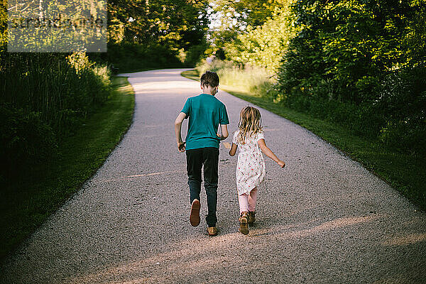 Bruder und Schwester laufen den Weg durch den grünen Wald entlang
