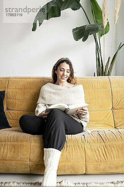 Schönes Mädchen auf einem Sofa  das ein Buch liest