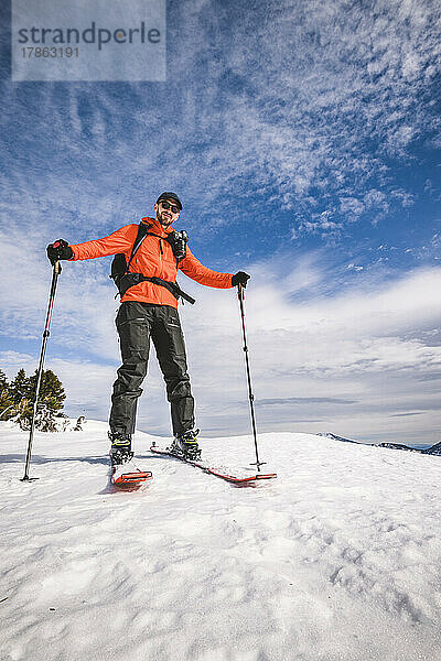 Backcountry-Skifahrer mit roter Jacke  Kamera und Fellen