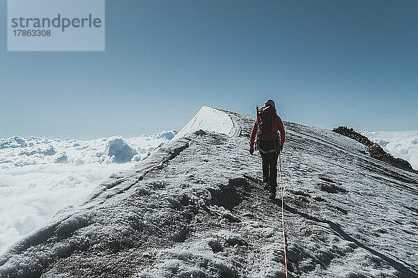 Bergsteigerin klettert die letzten Meter über den Grat in Richtung Gipfel