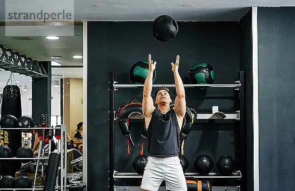 Mann macht Kräftigungsübungen mit Ball auf der Matte im Fitnessstudio