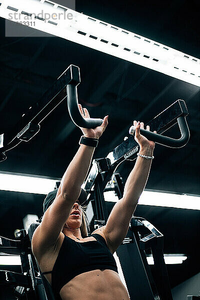 Junge erwachsene Frau trainiert im Fitnessstudio und trägt einen schwarzen Sport-BH