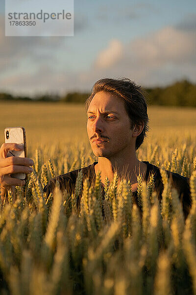 Französischer Mann macht bei Sonnenuntergang ein Foto mit dem Smartphone