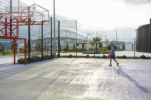 Ein Junge spielt mit einem Basketball auf dem Spielplatz.